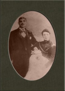 Sepia photograph of David Taylor and Julia Cook. holding their first born daughter May Eleanor.