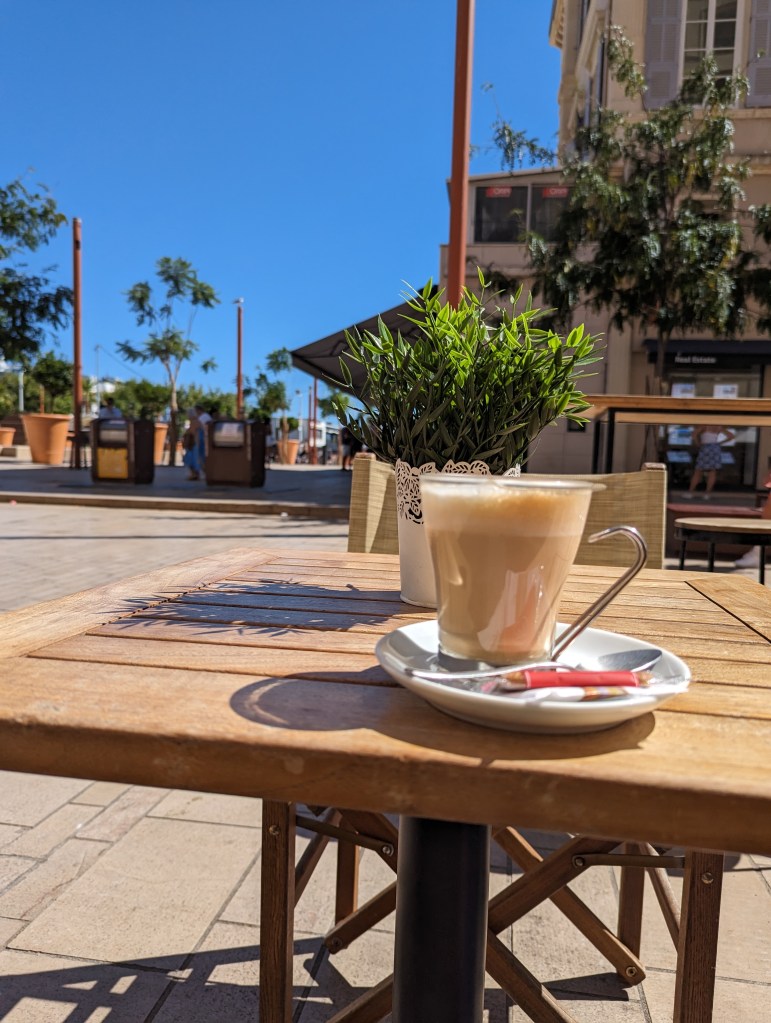 A coffee on a cafe table with a sunny street in the background.