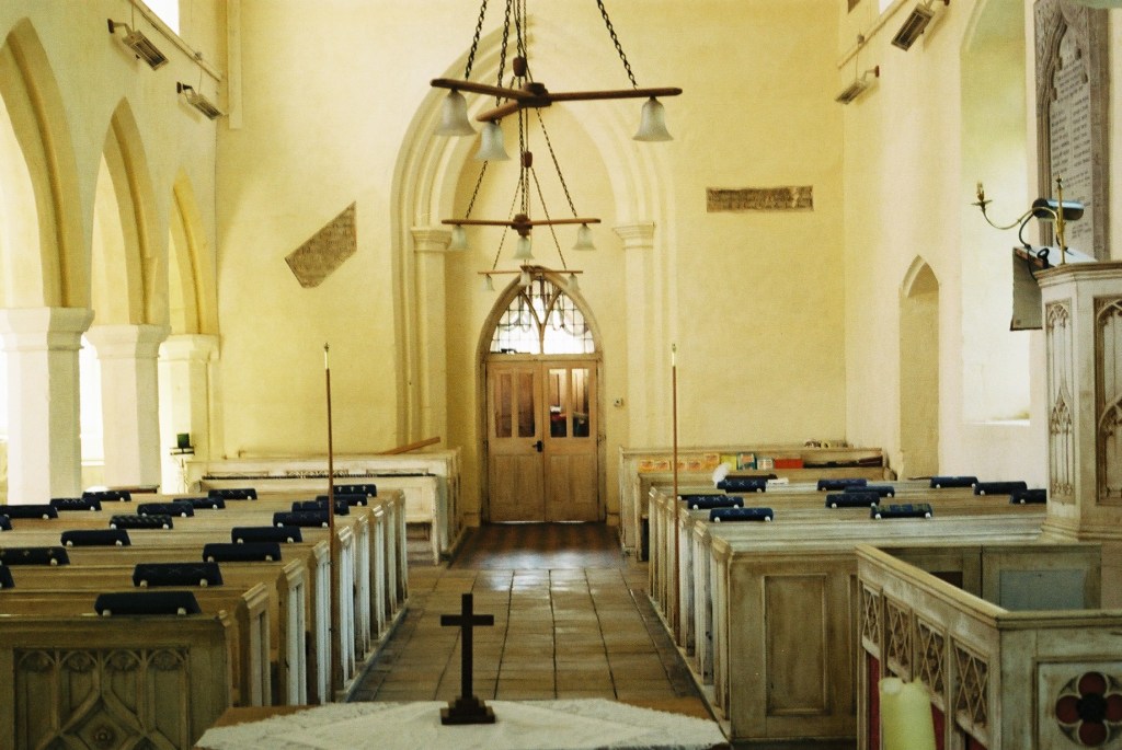 The interior of a country church with wooden pews and cream coloured walls